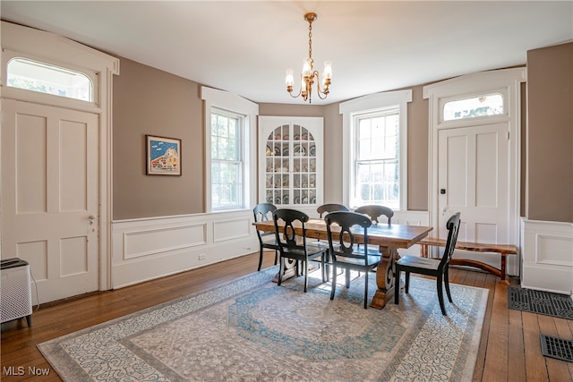 dining area with plenty of natural light, dark wood-type flooring, and an inviting chandelier