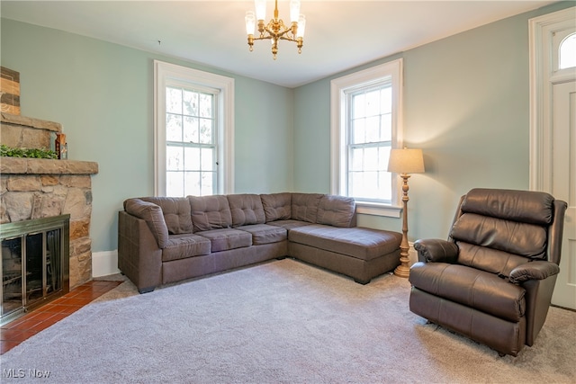 living room featuring plenty of natural light, tile patterned floors, an inviting chandelier, and a stone fireplace