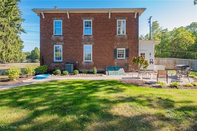 rear view of house with cooling unit, a yard, and a patio area