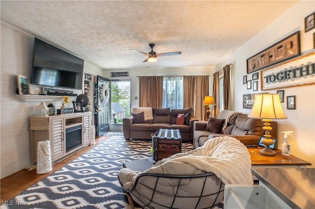 living room with a fireplace, wood-type flooring, a textured ceiling, and ceiling fan