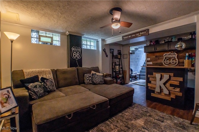 living room featuring ceiling fan, a textured ceiling, crown molding, and dark hardwood / wood-style flooring