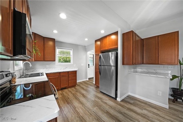 kitchen featuring light stone counters, sink, stainless steel appliances, and hardwood / wood-style floors