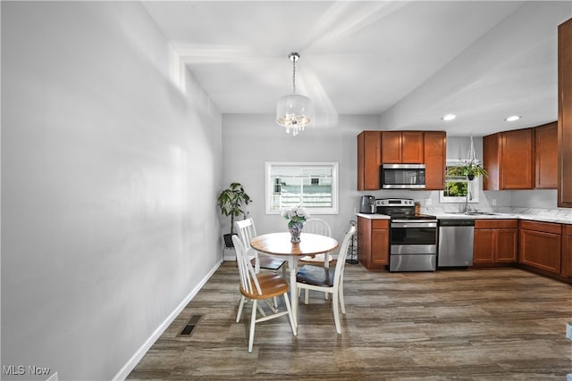 kitchen with sink, stainless steel appliances, hanging light fixtures, and dark hardwood / wood-style floors