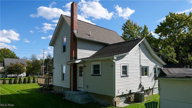 back of house featuring central air condition unit and a yard