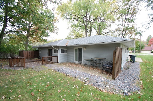 back of house featuring a deck and a lawn