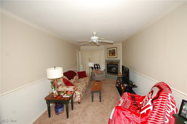 carpeted living room with ceiling fan, a fireplace, and crown molding