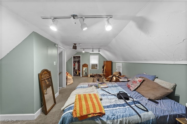 carpeted bedroom with lofted ceiling, track lighting, a walk in closet, and a closet