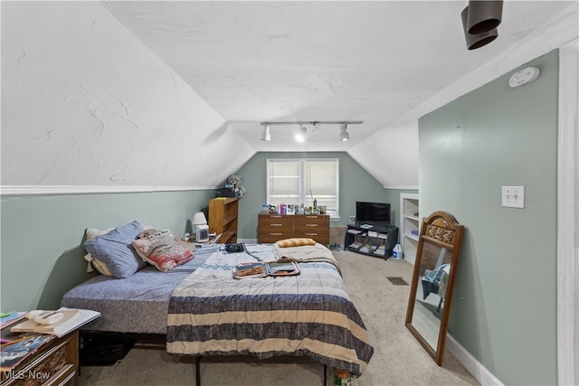 carpeted bedroom with track lighting and vaulted ceiling