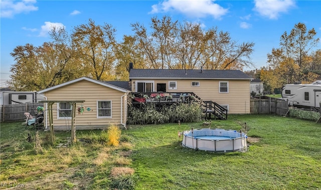 back of property with a swimming pool side deck and a yard