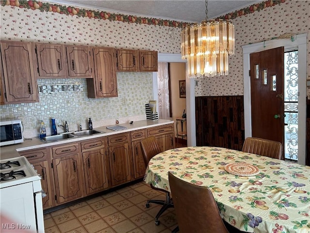 kitchen featuring a notable chandelier, sink, white range with gas cooktop, a wealth of natural light, and pendant lighting