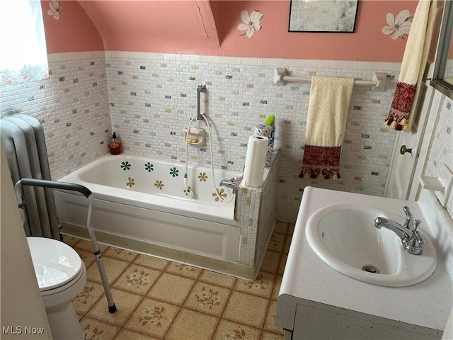 bathroom featuring toilet, tile walls, vanity, a tub, and tile patterned flooring