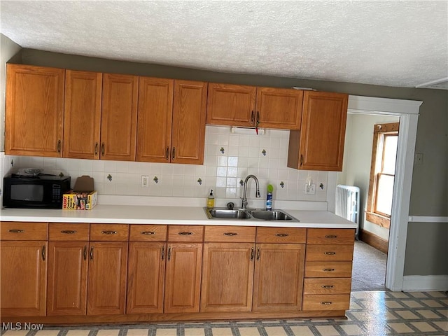 kitchen featuring tasteful backsplash, radiator, sink, and a textured ceiling