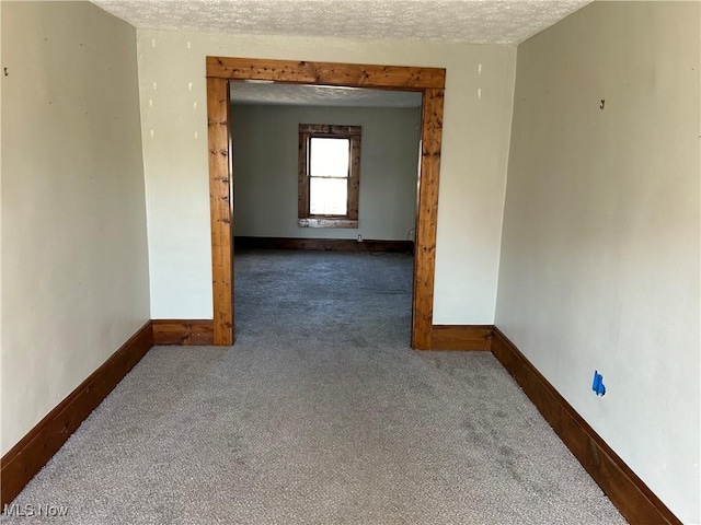 empty room with a textured ceiling and dark carpet