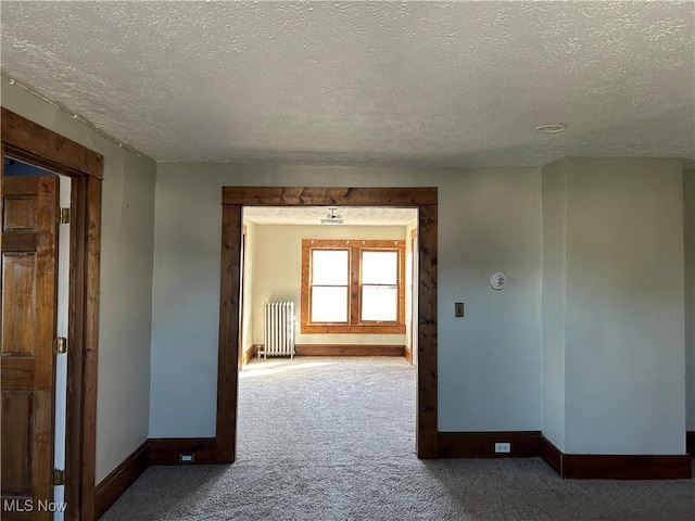 hallway featuring radiator heating unit, a textured ceiling, and carpet