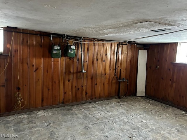 basement featuring wooden walls and a textured ceiling