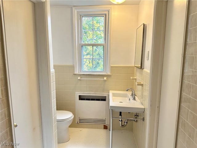 bathroom featuring radiator, sink, tile walls, and toilet