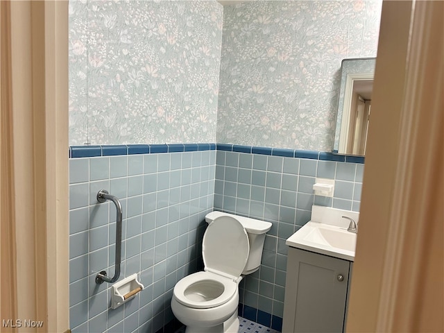 bathroom with toilet, tile walls, and vanity