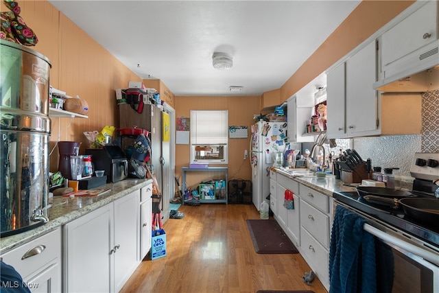 kitchen featuring white cabinetry, light wood-type flooring, stove, and white refrigerator