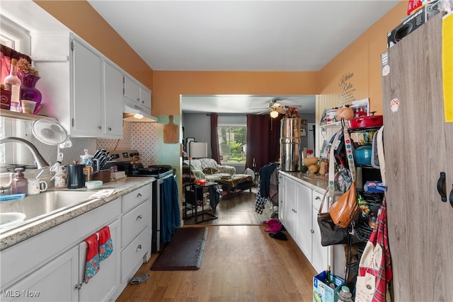 kitchen featuring sink, stainless steel range with electric cooktop, white cabinetry, ceiling fan, and light hardwood / wood-style flooring