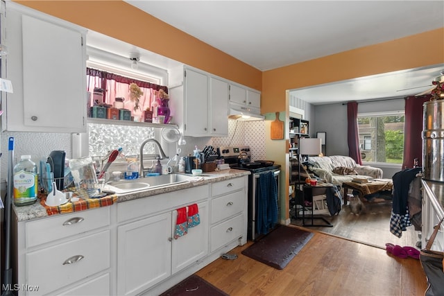 kitchen with hardwood / wood-style floors, white cabinets, sink, and stainless steel range with electric cooktop