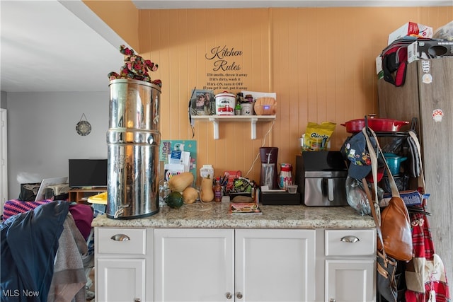 kitchen featuring white cabinetry and wood walls