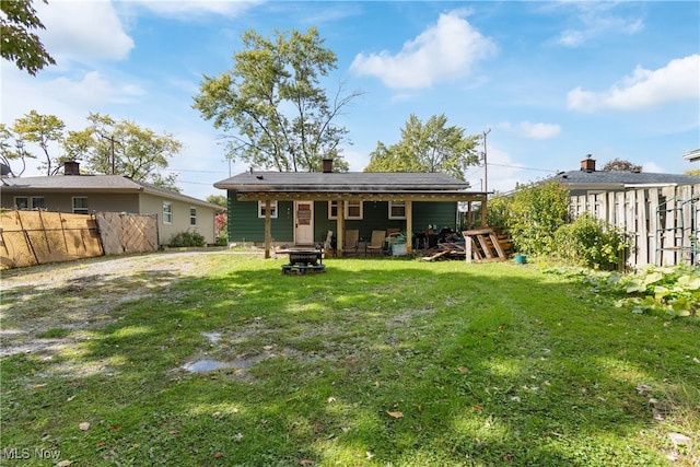 rear view of house with a fire pit and a lawn