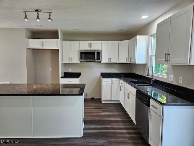 kitchen featuring appliances with stainless steel finishes, sink, dark hardwood / wood-style flooring, white cabinets, and dark stone countertops