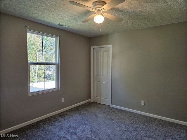 carpeted spare room featuring ceiling fan and a textured ceiling