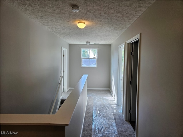 corridor with carpet and a textured ceiling