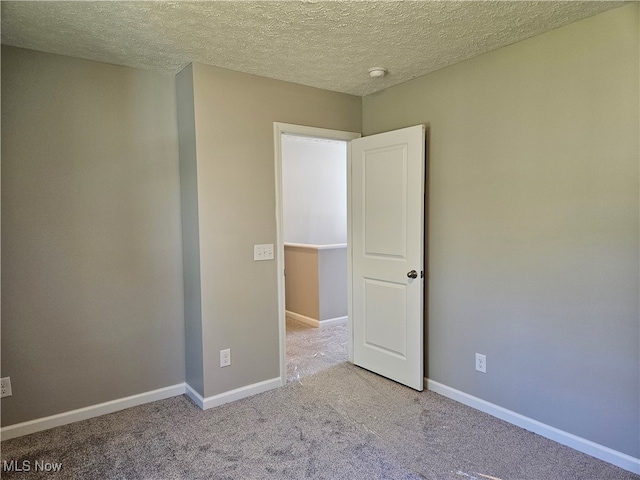 spare room featuring a textured ceiling and light colored carpet