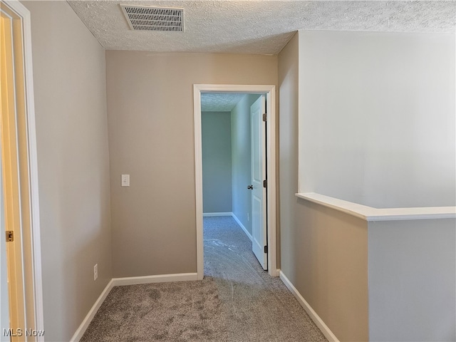 hallway featuring light carpet and a textured ceiling