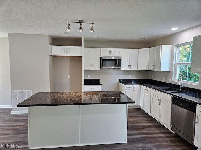 kitchen featuring dark hardwood / wood-style floors, stainless steel appliances, sink, a center island, and white cabinets