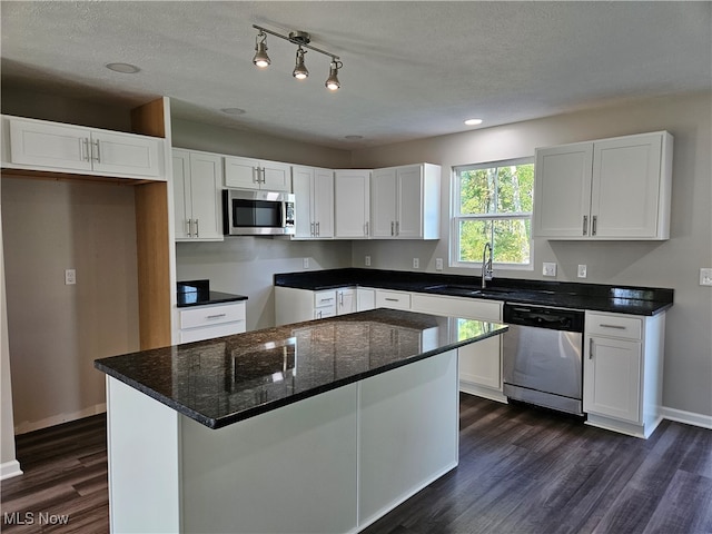 kitchen featuring appliances with stainless steel finishes, a textured ceiling, white cabinetry, dark hardwood / wood-style floors, and sink