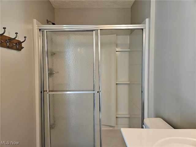 bathroom featuring toilet, a textured ceiling, walk in shower, and vanity