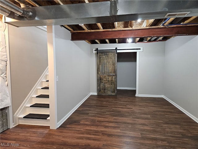 basement featuring dark wood-type flooring and a barn door