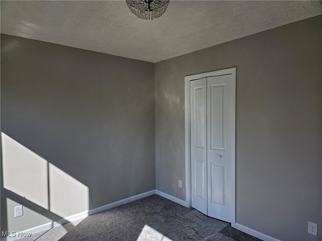 unfurnished bedroom featuring a closet, a textured ceiling, and dark carpet