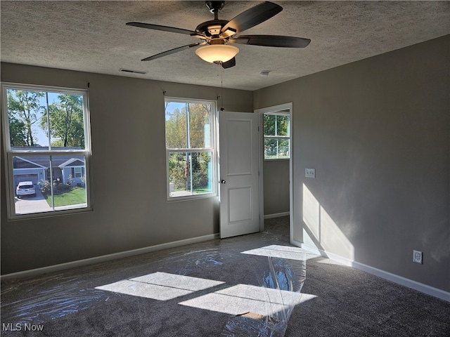 carpeted spare room with a textured ceiling and ceiling fan