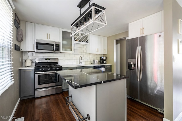 kitchen with a kitchen island, a kitchen breakfast bar, stainless steel appliances, white cabinets, and dark hardwood / wood-style flooring