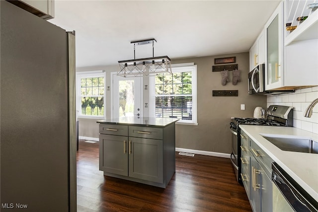 kitchen featuring gray cabinets, appliances with stainless steel finishes, hanging light fixtures, and dark hardwood / wood-style flooring