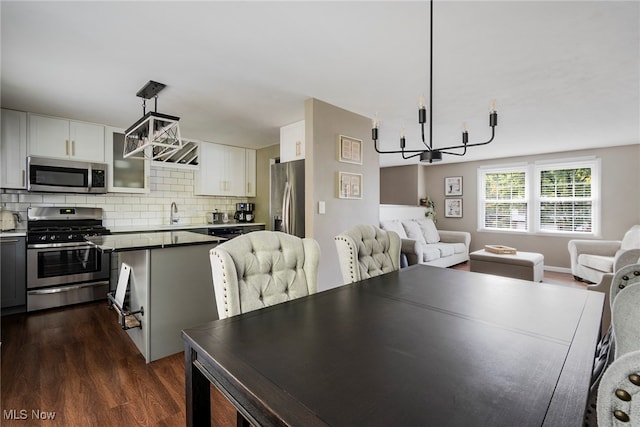 dining room featuring sink, dark hardwood / wood-style flooring, and an inviting chandelier