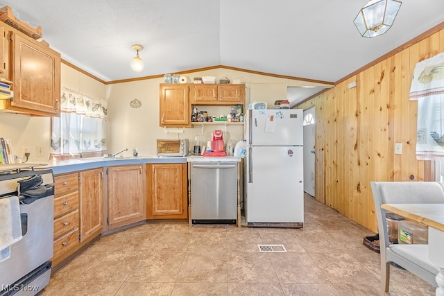 kitchen with stainless steel appliances, vaulted ceiling, plenty of natural light, and wood walls