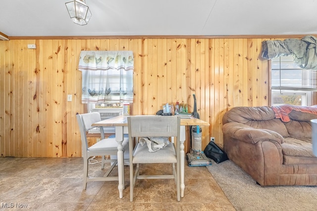 dining area featuring wooden walls, crown molding, and a healthy amount of sunlight