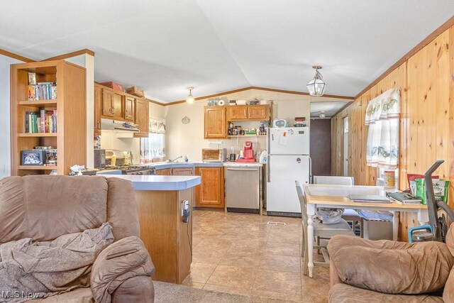 kitchen with wooden walls, kitchen peninsula, stainless steel appliances, ornamental molding, and vaulted ceiling