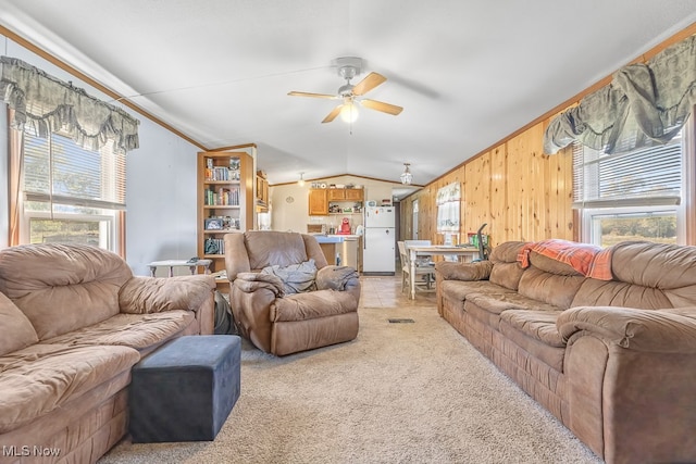 carpeted living room with lofted ceiling, wooden walls, crown molding, and ceiling fan