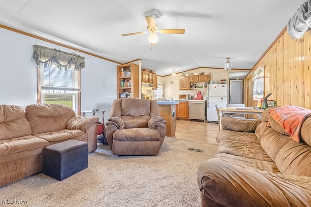 living room featuring lofted ceiling, wooden walls, light carpet, crown molding, and ceiling fan