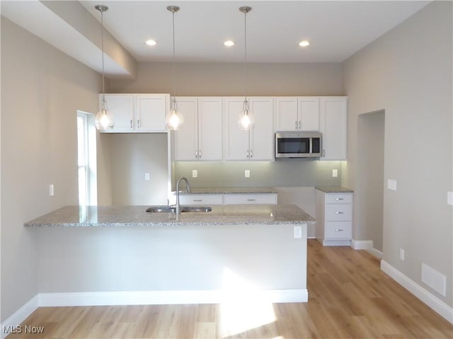 4424 W 53rd St, Cleveland, OH 44109 - kitchen featuring stainless steel microwave, a sink, light stone counters, a peninsula, and white cabinets
