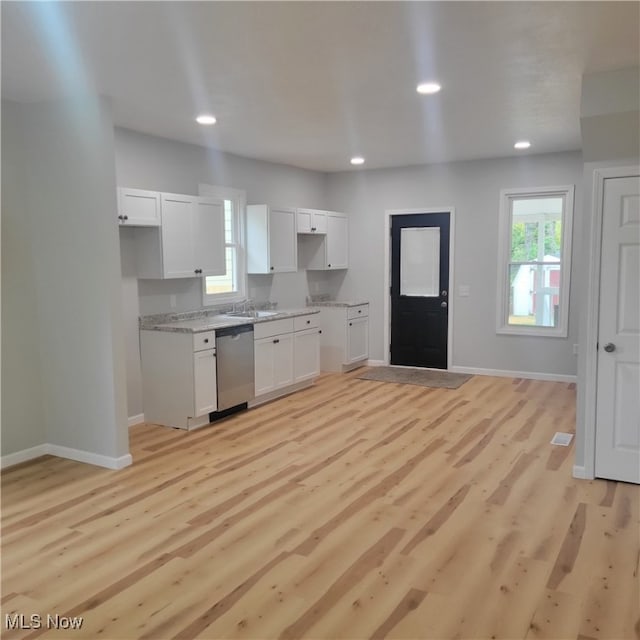 kitchen featuring stainless steel dishwasher, sink, white cabinetry, and light hardwood / wood-style flooring