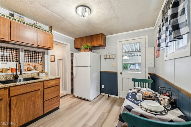 kitchen featuring sink, crown molding, white fridge, a textured ceiling, and light hardwood / wood-style floors