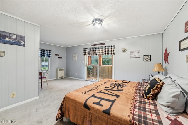 bedroom with ornamental molding, wood walls, a textured ceiling, and light colored carpet