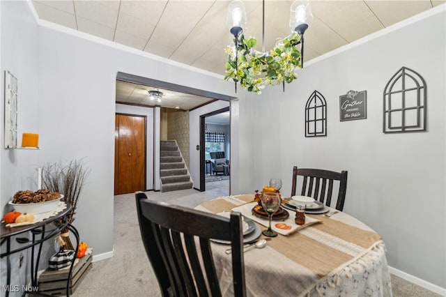 carpeted dining room with ornamental molding